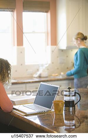 Young woman drinking coffee and working on her laptop in the morning View Large Photo Image Stock Photo - Young woman drinking coffee and working on her laptop in the morning. Fotosearch