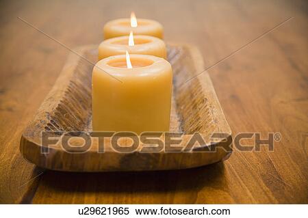 Stock Photography - Detail of three lit candles on wooden holder. Fotosearch