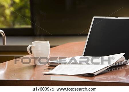 Stock Photography - Laptop, Coffee Mug, and Newspaper on Kitchen Counter. Fotosearch