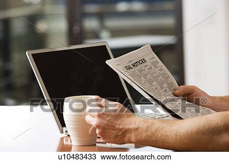 Stock Image - Man Reading Newspaper with Laptop and Coffee. Fotosearch