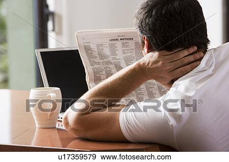 Stock Photo - Man Reading Newspaper with Laptop and Coffee. Fotosearch