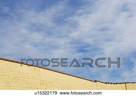 Brick wall against cloudy blue sky View Large Photo Image Stock Photo - Brick wall against cloudy blue sky. Fotosearch