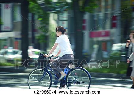 Woman riding bicycle in street View Large Photo Image Picture - Woman riding bicycle in street. Fotosearch