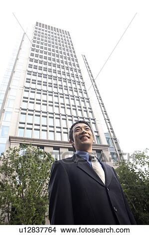 Businessman and a high-rise building View Large Photo Image Picture - Businessman and a high-rise building. Fotosearch