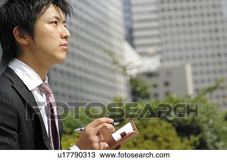 Stock Image - Businessman writing a schedule to the notebook. Fotosearch
