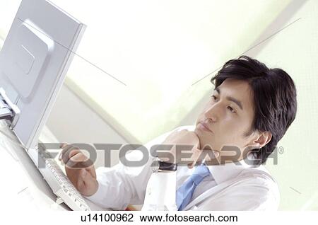 Stock Image - Office worker who gazes at the PC. Fotosearch