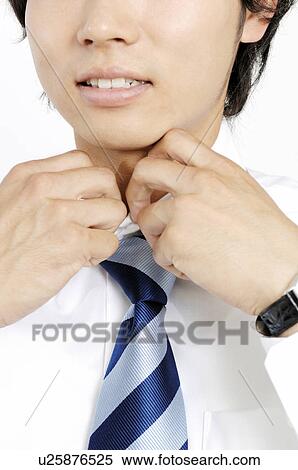 Businessman putting on a necktie View Large Photo Image Stock Photography - Businessman putting on a necktie. Fotosearch