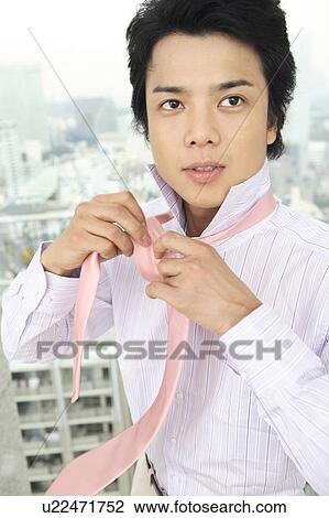 Stock Image - Businessman putting on a tie. Fotosearch