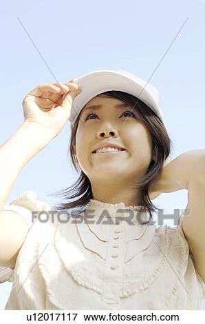 Woman who puts on a hat View Large Photo Image Stock Photo - Woman who puts on a hat. Fotosearch