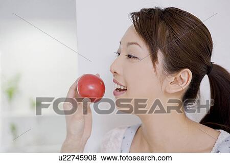 Woman who eats a tomato View Large Photo Image Stock Photo - Woman who eats a tomato. Fotosearch
