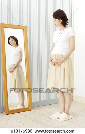 Pregnant woman watching a mirror View Large Photo Image Stock Photograph - Pregnant woman watching a mirror. Fotosearch
