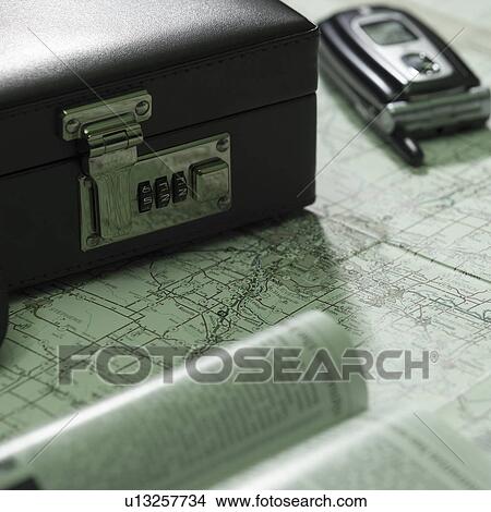 Picture - Briefcase and mobile phone on map. Fotosearch