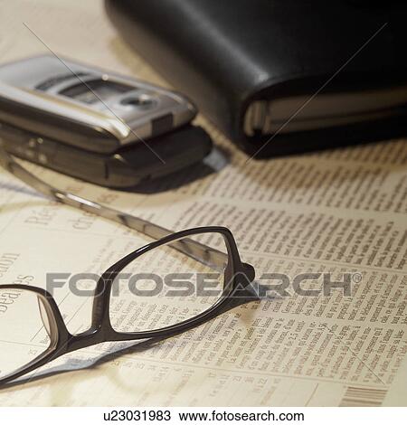 Stock Image - Mobile phone and glasses on newspaper. Fotosearch