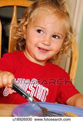 Stock Image - Close-up of a girl eating food with a fork. Fotosearch