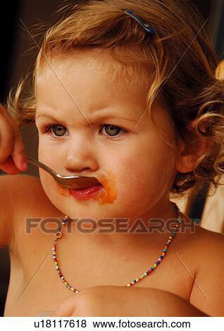 Stock Photo - Close-up of a girl eating jam with a spoon. Fotosearch