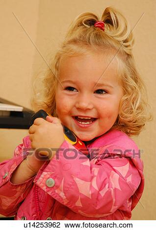 Stock Image - Close-up of a girl holding a toy camera and smiling. Fotosearch