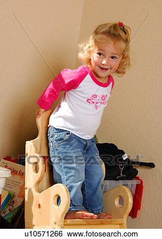 Close-up of a girl standing on a chair and smiling View Large Photo Image Stock Photograph - Close-up of a girl standing on a chair and smiling. Fotosearch