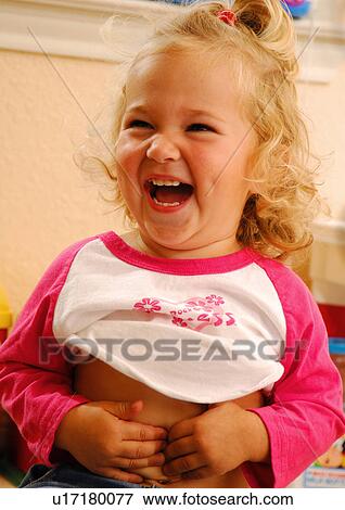 Stock Photo - Close-up of a girl touching her belly button and laughing. Fotosearch