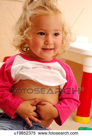 Close-up of a girl touching her belly button and smiling View Large Photo Image Stock Photography - Close-up of a girl touching her belly button and smiling. Fotosearch