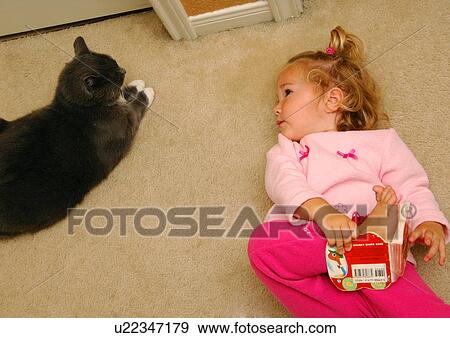 High angle view of a girl lying on the floor and looking at a cat View Large Photo Image Stock Photo - High angle view of a girl lying on the floor and looking at a cat. Fotosearch