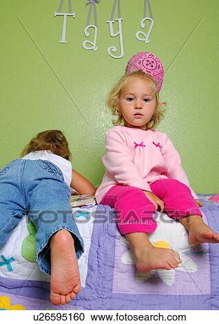 Portrait of a girl sitting on the bed with her sister lying on the bed beside her View Large Photo Image Stock Image - Portrait of a girl sitting on the bed with her sister lying on the bed beside her. Fotosearch
