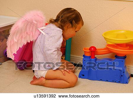 Side profile of a girl kneeling on the floor and looking at a toy View Large Photo Image Stock Image - Side profile of a girl kneeling on the floor and looking at a toy. Fotosearch