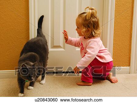 Stock Image - Side profile of a girl playing with a cat. Fotosearch