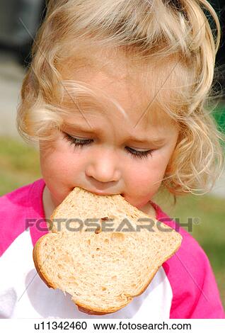 Stock Image - Close-up of a girl eating a slice of bread. Fotosearch