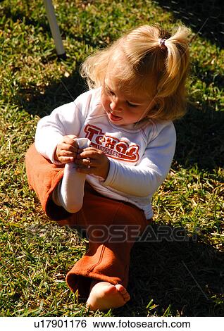 Stock Photograph - Close-up of a girl putting off her sock. Fotosearch