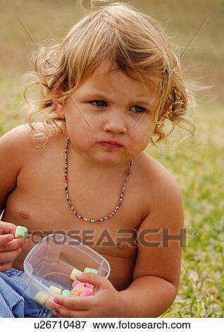 Stock Photo - Close-up of a girl sitting and holding candies. Fotosearch