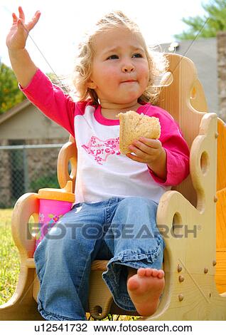 Close-up of a girl sitting in a chair and eating a slice of bread View Large Photo Image Stock Image - Close-up of a girl sitting in a chair and eating a slice of bread. Fotosearch