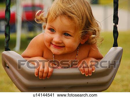 Stock Image - Close-up of a girl swinging on a swing. Fotosearch