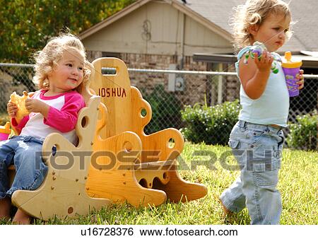 Girl sitting in a chair and looking at her sister walking beside her View Large Photo Image Stock Photograph - Girl sitting in a chair and looking at her sister walking beside her. Fotosearch