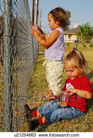 Girl sitting in a park with her sister standing beside her View Large Photo Image Stock Image - Girl sitting in a park with her sister standing beside her. Fotosearch