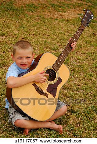 Stock Photo - Portrait of a boy playing a guitar and smiling. Fotosearch