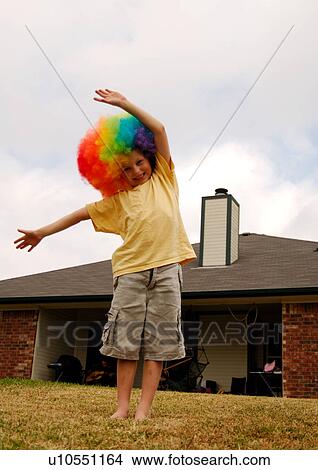 Picture - Portrait of a boy wearing a multi-colored wig and smiling. Fotosearch