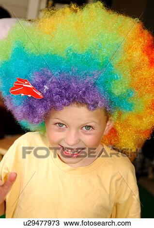Stock Image - Portrait of a boy wearing a multi-colored wig and smiling. Fotosearch