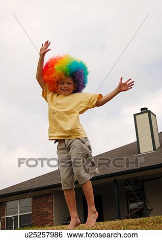 Stock Photograph - Portrait of a boy wearing a multi-colored wig and smiling. Fotosearch