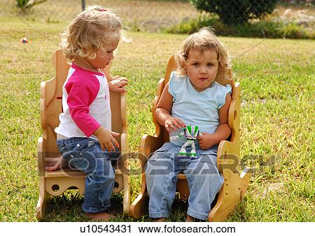 Portrait of a girl holding a toy and her sister looking at the toy View Large Photo Image Stock Image - Portrait of a girl holding a toy and her sister looking at the toy. Fotosearch
