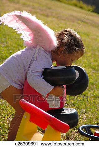 Side profile of a girl picking up a tricycle View Large Photo Image Stock Image - Side profile of a girl picking up a tricycle. Fotosearch