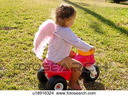 Picture - Side profile of a girl riding a tricycle. Fotosearch