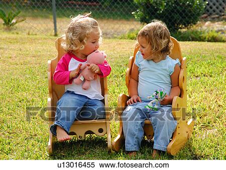 Two girls sitting on chairs and holding toys View Large Photo Image Stock Photography - Two girls sitting on chairs and holding toys. Fotosearch