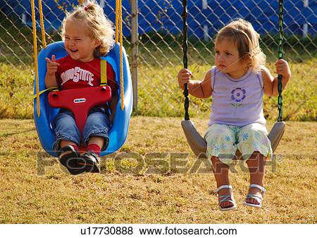 Two girls swinging in swings View Large Photo Image Stock Photo - Two girls swinging in swings. Fotosearch
