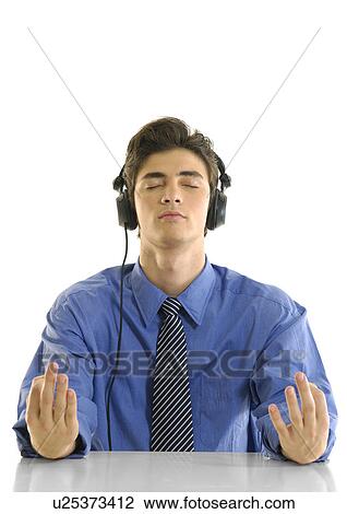 Stock Image - Businessman practicing yoga and listening to music. Fotosearch