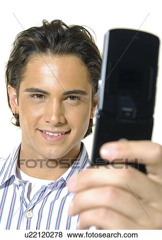 Close-up of a young man text messaging with a mobile phone and smiling View Large Photo Image Stock Photo - Close-up of a young man text messaging with a mobile phone and smiling. Fotosearch