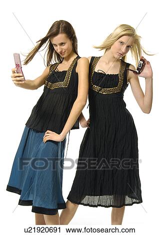 Portrait of a young woman showing a photograph with another young woman taking a photograph with a mobile phone View Large Photo Image Stock Image - Portrait of a young woman showing a photograph with another young woman taking a photograph with a mobile phone. Fotosearch