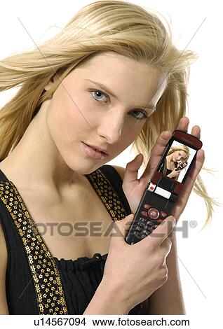 Portrait of a young woman showing her photograph in a mobile phone View Large Photo Image Picture - Portrait of a young woman showing her photograph in a mobile phone. Fotosearch