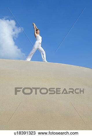 Stock Image - Low angle view of a young man practicing yoga. Fotosearch