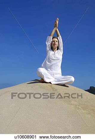 Low angle view of a young woman practicing yoga with her arms crossed View Large Photo Image Stock Image - Low angle view of a young woman practicing yoga with her arms crossed. Fotosearch