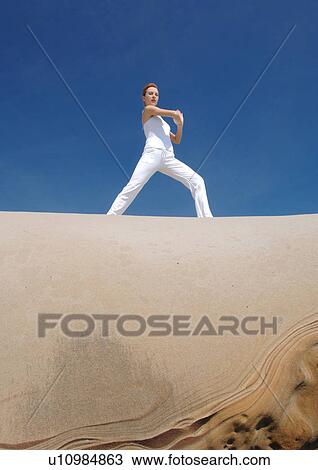 Low angle view of a young woman practicing yoga View Large Photo Image Stock Image - Low angle view of a young woman practicing yoga. Fotosearch